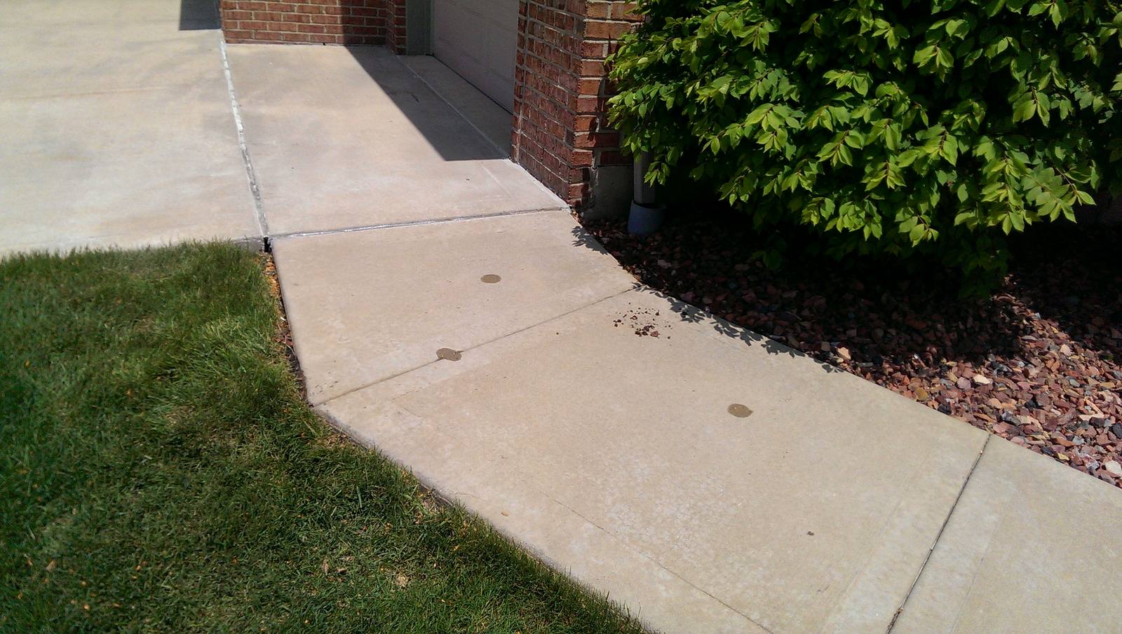 A raised concrete walkway sitting back at level beside a garage